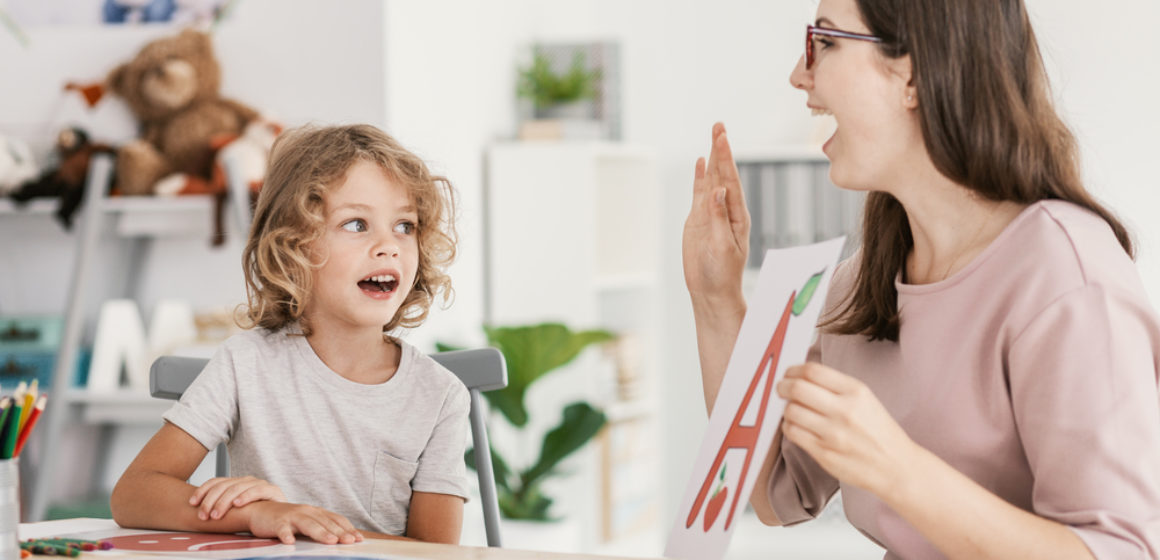 Speech therapist teaching letter pronunciation to a young boy in